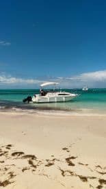 A boat is anchored at a beautiful beach with turquoise waters, showcasing a perfect day for water activities and relaxation.
