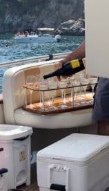 A hand pours champagne into glasses on a boat, showcasing a luxurious onboard bar setup perfect for celebrations and gatherings on the water.