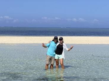 A joyful couple poses in shallow water at a picturesque sandbar, capturing a fun moment during their beach adventure.