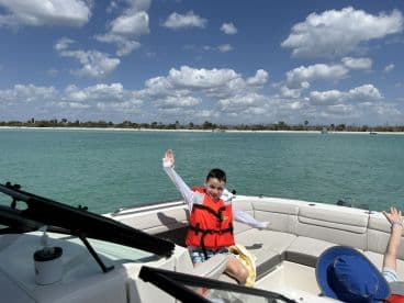 A joyful child waves from the deck of a boat, enjoying a sunny day on the water — perfect for family outings and adventures.