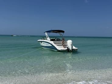A child enjoys a sunny day on a boat anchored near the beach, highlighting a perfect family outing on the water.