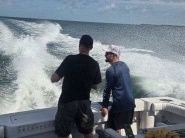 Two friends enjoy a day on the water, taking in the scenery from the deck of their boat — a perfect moment for camaraderie and adventure.