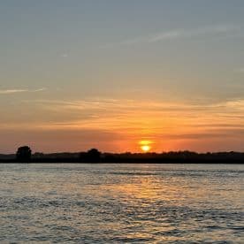 A serene sunset over calm waters, creating a picturesque backdrop perfect for evening boat cruises.