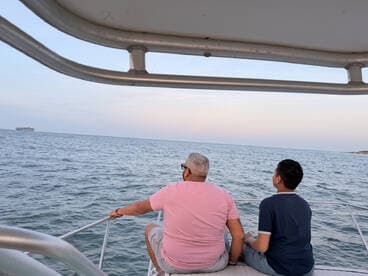A family enjoys a serene moment on a boat, gazing out at the ocean during sunset — a perfect setting for creating lasting memories.