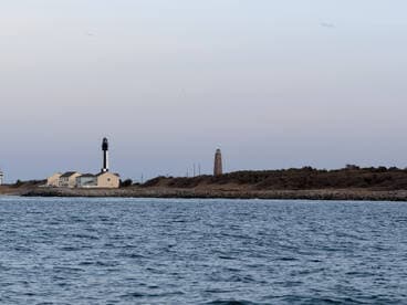 A serene view of two lighthouses along the coastline, showcasing the beauty of maritime landmarks against a tranquil sky.