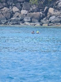 Two snorkelers enjoy a refreshing swim in crystal-clear waters, surrounded by rocky shores — a perfect family adventure in the great outdoors.