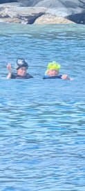 Two individuals enjoy a refreshing swim in clear waters, showcasing a fun and adventurous day on the water.