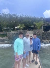 A cheerful family poses together at a beachside location, capturing a memorable moment during their tropical getaway.
