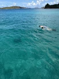 A snorkeler explores the vibrant underwater world in crystal-clear waters, surrounded by picturesque islands — a perfect adventure for water enthusiasts.