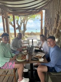 A family enjoys a delicious meal together at a beachfront restaurant, surrounded by stunning ocean views — perfect for a relaxing day out on the water.