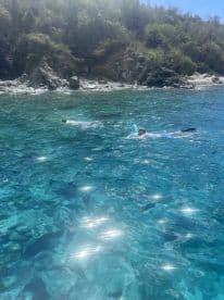 Two snorkelers explore the vibrant underwater world in crystal-clear waters, surrounded by stunning natural scenery — a perfect adventure for water enthusiasts.