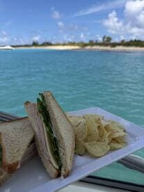A delicious sandwich accompanied by chips, perfect for enjoying on a boat trip in the beautiful turquoise waters.