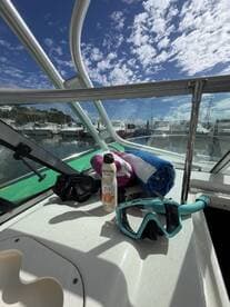 A collection of snorkeling gear, sunscreen, and towels laid out on the deck of a boat, ready for a day of adventure on the water.