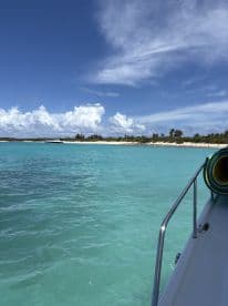 A stunning view of a boat cruising through crystal-clear turquoise waters, showcasing the beautiful coastline and vibrant sky — perfect for a day of exploration and relaxation on the water.
