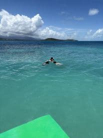 A group enjoys a refreshing swim in crystal-clear waters, surrounded by stunning scenery — perfect for family fun and beach adventures.