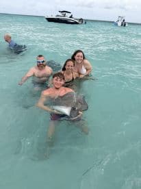 A group of friends enjoys an unforgettable experience swimming with stingrays in the clear waters, capturing the thrill of wildlife interaction in a tropical paradise.