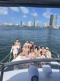 A lively group enjoys a day on the water, celebrating aboard a boat with the Miami skyline in the background — perfect for summer parties and gatherings.