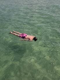 A child enjoys swimming in crystal-clear waters, showcasing the perfect setting for snorkeling adventures and family fun on the water.