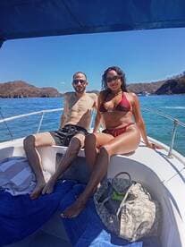 A couple enjoys a sunny day on a boat, soaking up the sun and relaxing by the ocean — a perfect getaway for beach lovers.