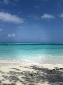 A serene beach scene featuring turquoise waters and a clear blue sky, perfect for showcasing tropical destinations.