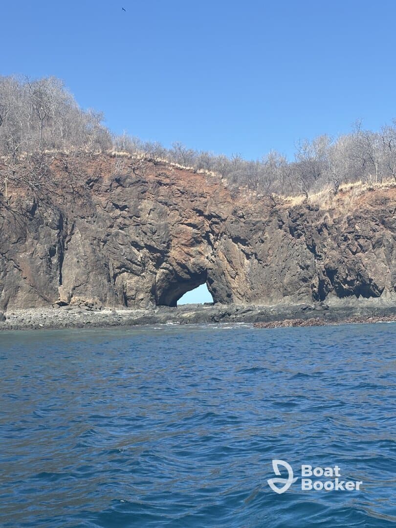 A stunning view of a natural rock arch along the coastline, showcasing the beauty of the surrounding waters and landscape — perfect for nature lovers and sightseeing tours.