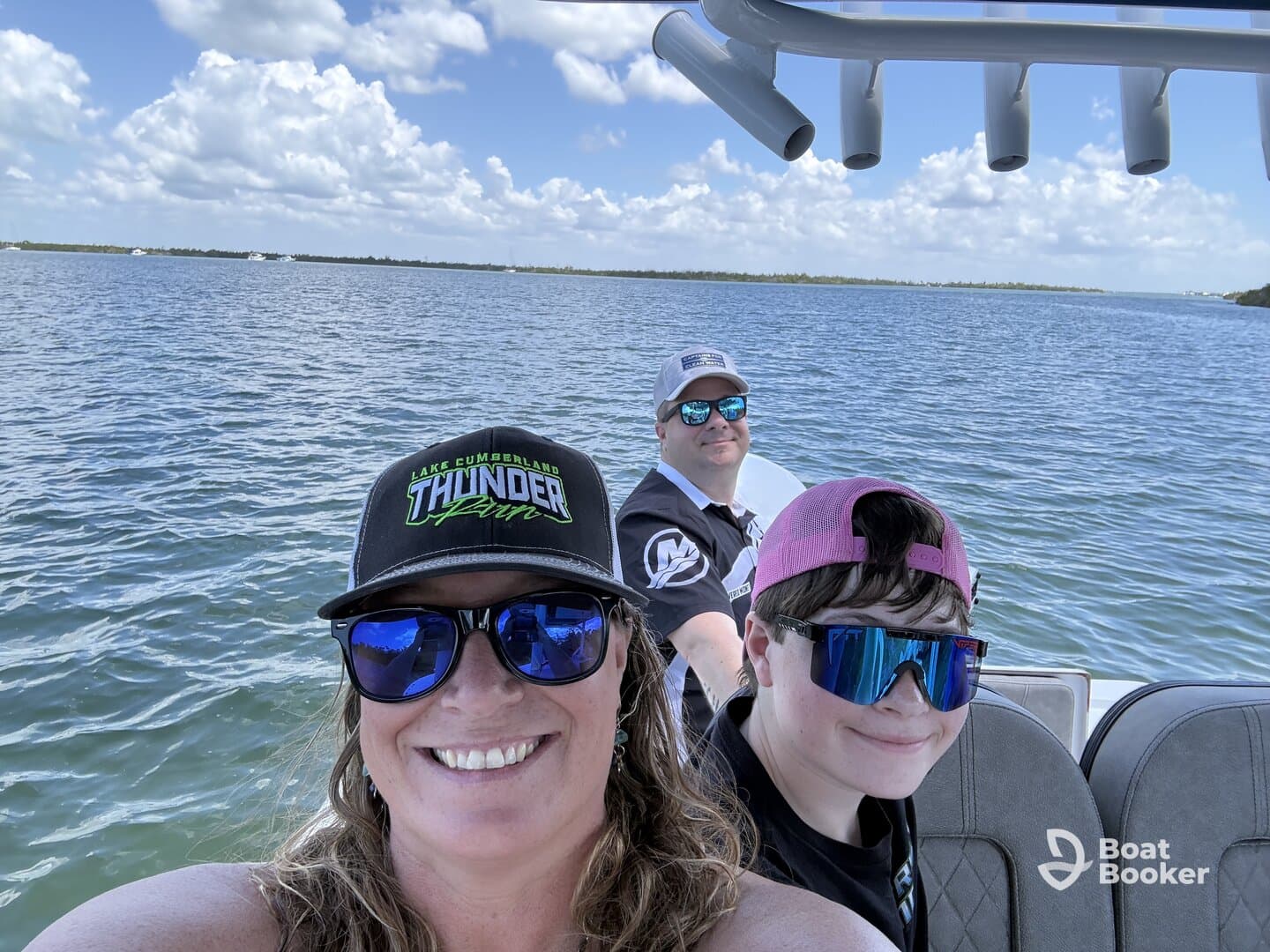 A joyful family enjoys a day on the water, capturing a fun moment aboard their boat with smiles and sunglasses under a bright sky.