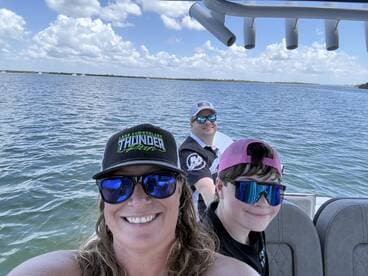 A joyful family enjoys a day on the water, capturing a fun moment aboard their boat with smiles and sunglasses under a bright sky.