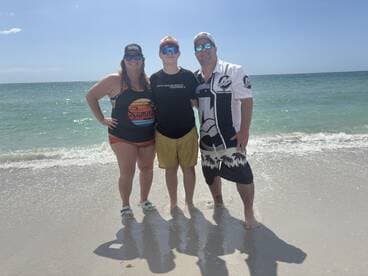 A cheerful group poses on the beach, enjoying a sunny day by the water — perfect for family outings and beach adventures.