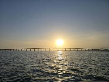 A stunning sunset view over the water, featuring a bridge silhouetted against the vibrant sky — perfect for capturing the beauty of evening boat trips.