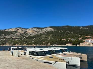 A scenic view of several yachts docked at a marina, surrounded by stunning mountainous terrain — perfect for exploring coastal destinations.