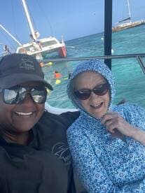 Two women enjoy a sunny day on the water, smiling for a selfie with a snorkeling adventure in the background — a perfect moment capturing the joy of ocean encounters.