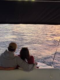 A couple enjoys a romantic moment on a boat, watching the sunset over the water with drinks in hand — an ideal setting for intimate getaways.