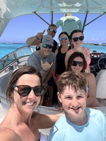 A joyful group of friends and family poses for a selfie aboard a boat, capturing the fun and excitement of their day on the water.