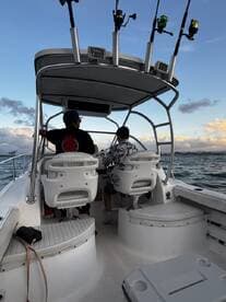 Inside view of a boat's helm area, featuring two individuals at the controls, showcasing the seating and console setup for an enjoyable day on the water.