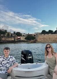 A cheerful duo enjoys a scenic boat ride, showcasing a beautiful waterfront backdrop — perfect for family outings and adventures on the water.