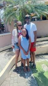 A joyful family poses together in a sunny outdoor setting, capturing a memorable moment during their vacation.