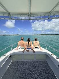 A group of friends enjoys a scenic view from the back of a boat, soaking in the sun and turquoise waters — perfect for a relaxing day on the water.
