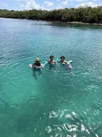 A group of friends enjoys a refreshing swim in crystal-clear waters, perfect for a day of fun and relaxation in the sun.