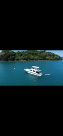 A beautiful scene featuring a boat anchored in tranquil waters, with people enjoying swimming and paddleboarding nearby — perfect for a day of adventure and relaxation on the water.