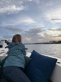 A woman enjoys a serene moment on a boat, gazing at the beautiful sunset over the water — a perfect setting for relaxation and reflection.