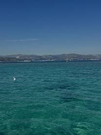 A serene view of clear turquoise waters and a distant coastline, perfect for showcasing the beauty of a day on the water.