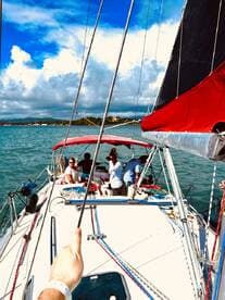 A lively group enjoys a sailing experience on a beautiful day, showcasing the joy of being on the water with friends.