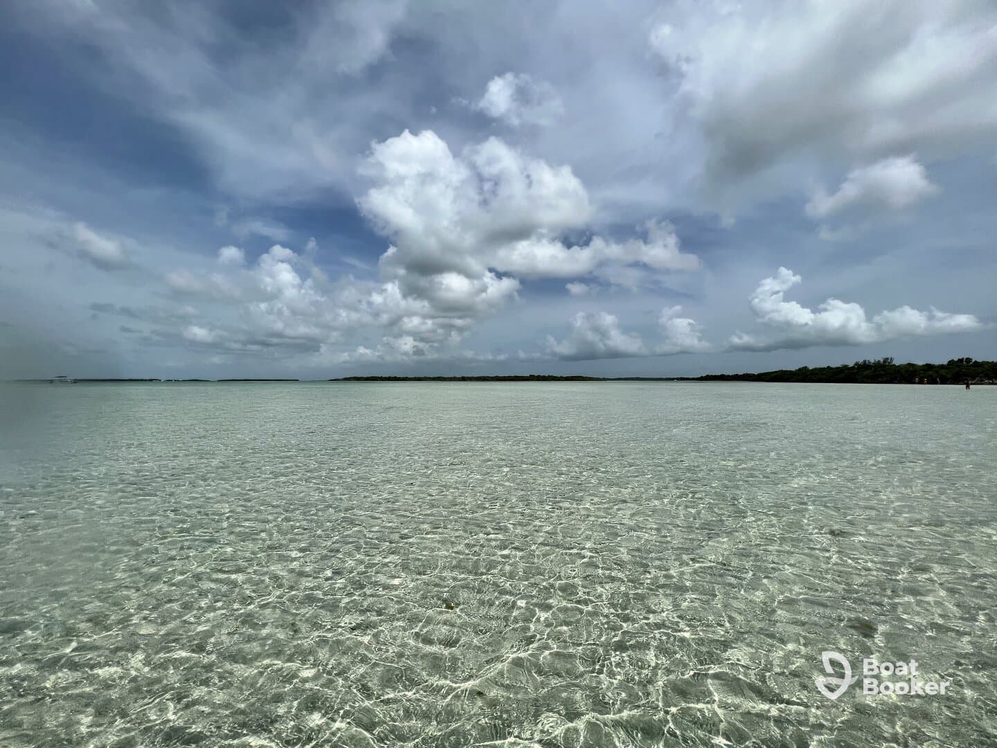 A stunning view of clear waters and a picturesque coastline under a cloudy sky, perfect for showcasing the beauty of a tropical destination.