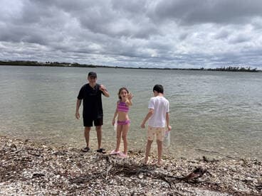 A family enjoys a day at the beach, with children exploring the shoreline and playing in the water — a perfect moment for family bonding and outdoor fun.