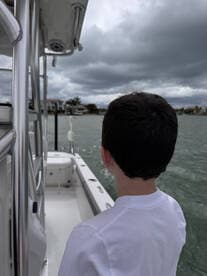 A young boy gazes out over the water from a boat, capturing a moment of adventure on the water, perfect for family outings.