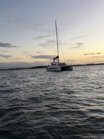 A beautiful catamaran sails through the water at sunset, showcasing its elegant design and perfect for serene evening cruises.