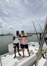 Two friends proudly display their catch aboard a boat, celebrating a successful fishing trip at the marina. Perfect for showcasing the thrill of fishing adventures on the water.