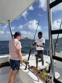 Two individuals engage in fishing activities aboard a boat, showcasing the excitement of a day on the water.