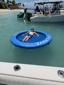 A young boy relaxes on a floating mat in the clear waters, enjoying a fun day at the beach — perfect for family outings and water activities.