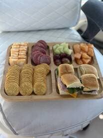 A beautifully arranged platter of snacks featuring crackers, meats, cheeses, and fruits, perfect for enjoying on a boat trip.